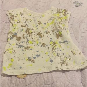 White shirt with blue, yellow, and gold paint.